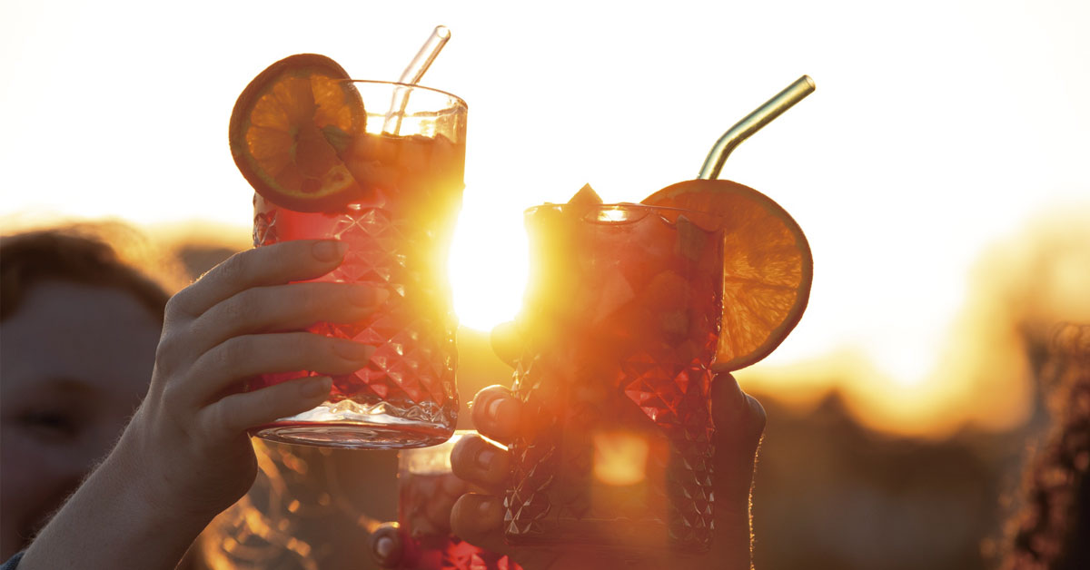 People toasting with cocktails at sunset